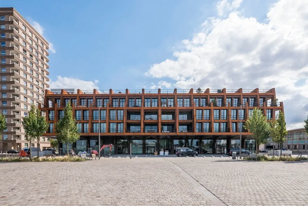Edificio moderno con fachada de acero color óxido junto a una plaza adoquinada