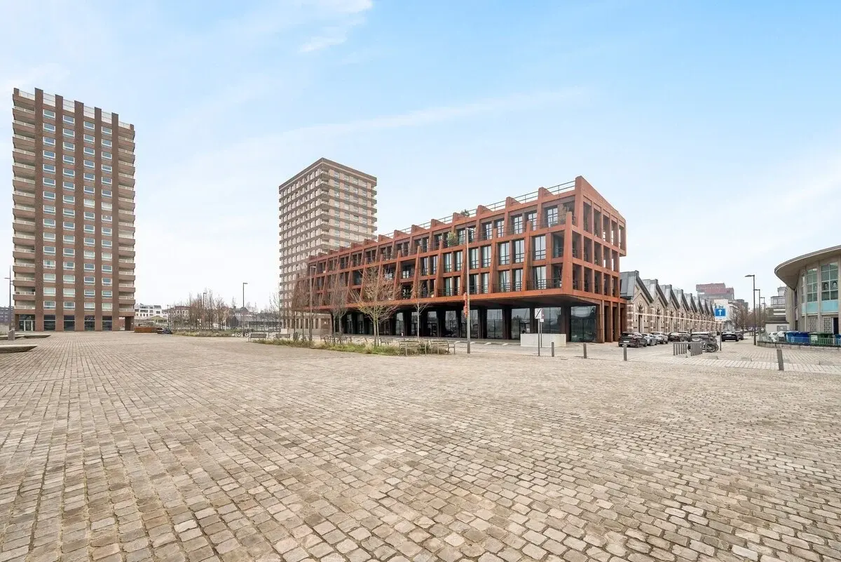 Edificio moderno con fachada de acero color óxido junto a una plaza adoquinada